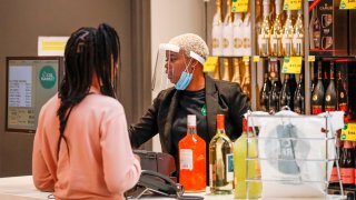 An employee wearing a face mask rings up a customer's alcohol purchase at the Local Market Foods store in Chicago, Illinois, on April 8, 2020, during the coronavirus outbreak.