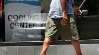 A man wearing shorts and sandals walks past a cooling center in a Chicago Department of Human Services center