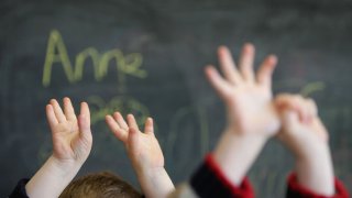 children raise hands in school