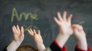 children raise hands in school