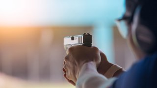 A person aiming a handgun at a gun range.
