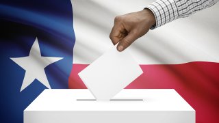 Mano colocando voto en una urna con la bandera de Texas en el fondo.