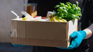 Home delivery during an epidemic. contactless delivery. Food donation. Men's hands hold a box with products.