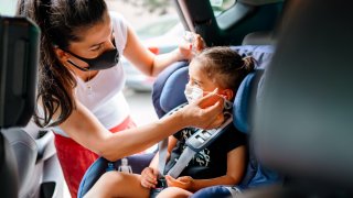Portrait of a mother fastening her daughter safely in a car seat