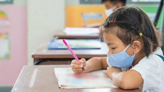 Niña en escuela con tapabocas