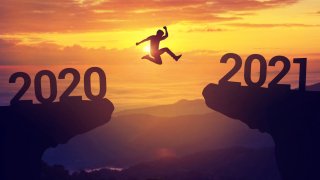 Foto conceptual de persona saltando entre un precipicio con los años 2020 y 2021 en los extremos