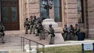 More than 100 Texas troopers, including dozens wearing tactical vests and carrying riot gear, stood on guard outside the state Capitol on Tuesday as lawmakers returned to work amid FBI warnings of armed protests at statehouses across the country.