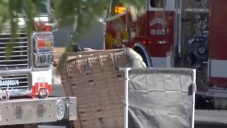 Fotografía de partes de dos vehículos de bomberos entre los que está la canastilla de un globo aerostáticos accidenteado.