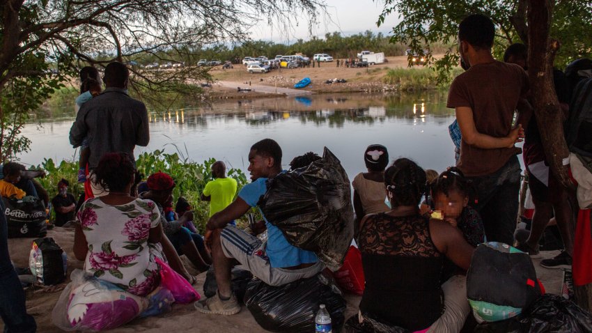CIUDAD ACUNA, MEXICO – SEPTEMBER 23: Haitian immigrants wait to cross the Rio Grande into Del Rio, Texas on September 23, 2021 from Ciudad Acuna, Mexico. On the U.S. side of the bridge (R), up to 14,000 immigrants had been encamped in squalid conditions. U.S. immigration officials say they have mostly cleared the camp of immigrants, deporting some and releasing others to pursue asylum claims in the United States. (Photo by John Moore/Getty Images)