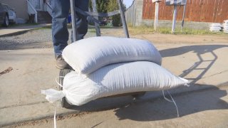 Two white sandbags on a handtruck