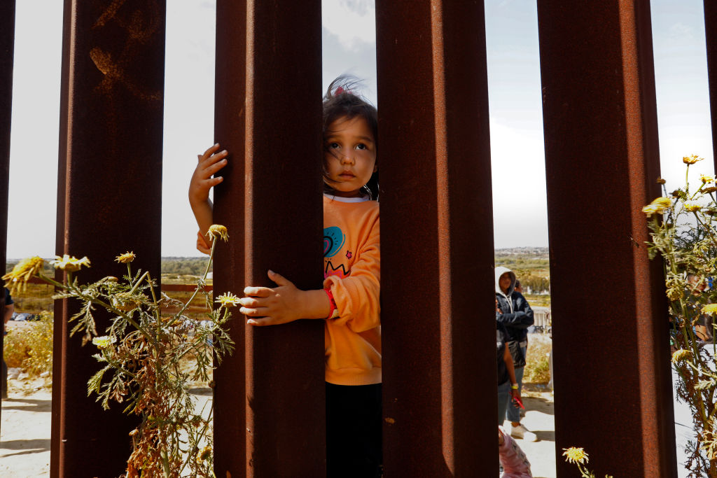Mahya, de 4 años, de Afganistán, está esperando con su madre, padre y cuatro hermanas externas para ingresar a los EEUU en la frontera entre EEUU y México en Tijuana. Su hermana dijo que la vida de sus cinco hijas era demasiado difícil en Afganistán bajo el régimen talibán. Migrantes que esperan cruzar a los Estados Unidos desde Tijuana, México, esperan en un área al sur del segundo muro fronterizo en previsión de un cambio en la política de inmigración, el Título 42, que puede permitirles solicitar asilo.  (Carolyn Cole / Los Angeles Times a través de Getty Images)
