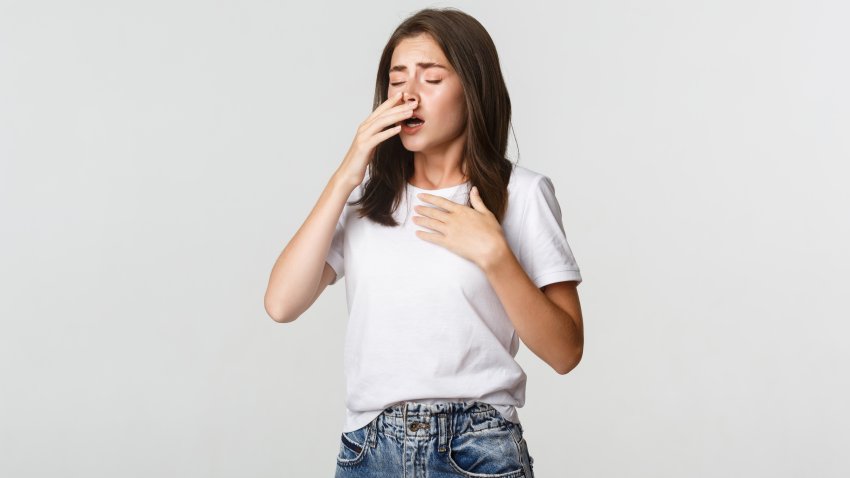 Young woman with allergy sneezing. Girl feeling sick having runny nose
