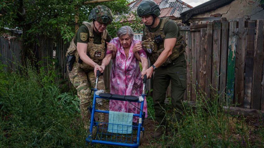 Agentes de la unidad de policía Ángeles Blancos ayudan a una mujer mayor a llegar a una camioneta durante una evacuación, en Toretsk, en la región ucraniana de Donetsk, el 28 de junio de 2024. (AP Foto/Evgeniy Maloletka)