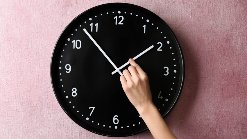 Woman changing time on big wall clock